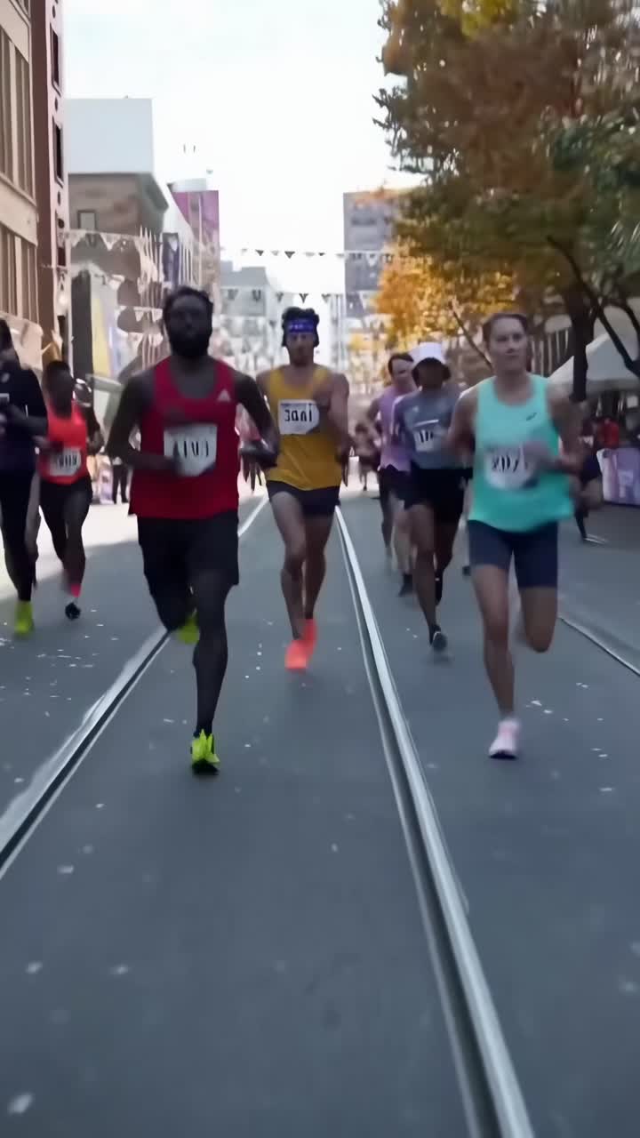 Videoaufnahme aus niedrigem Winkel von MarathonläuferInnen in einer Stadtstraße, die dynamische Bewegung einfängt