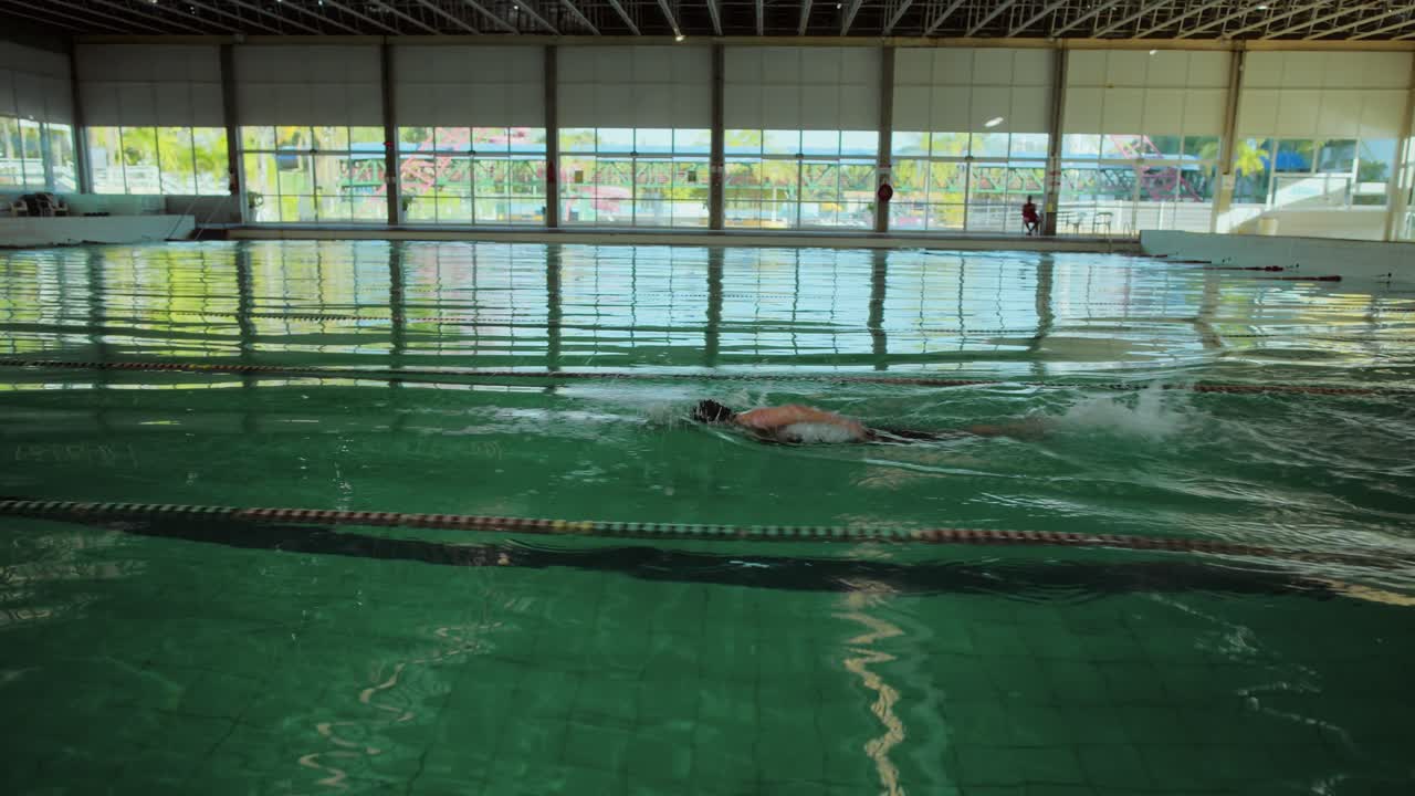 Person swimming laps in a bright indoor pool