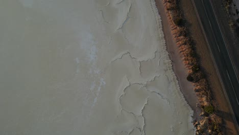 dried salt lake surrounding straight street in highlands of australia