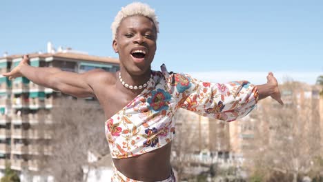 joyful black man in bright dress dancing on rooftop