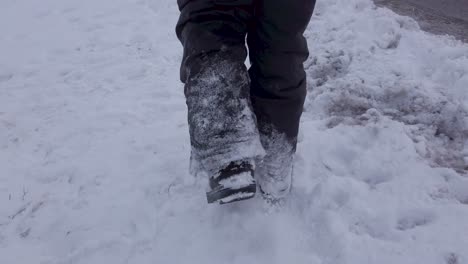 冬天穿着灰色雪裤和靴子的小孩在路边穿着雪