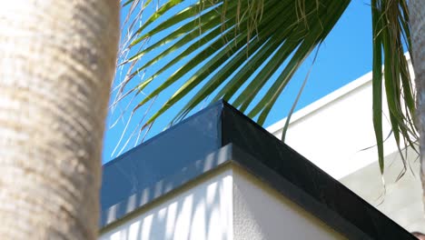 Slow-orbiting-shot-of-a-villa-balcony-surrounded-by-green-palm-trees-in-Sete