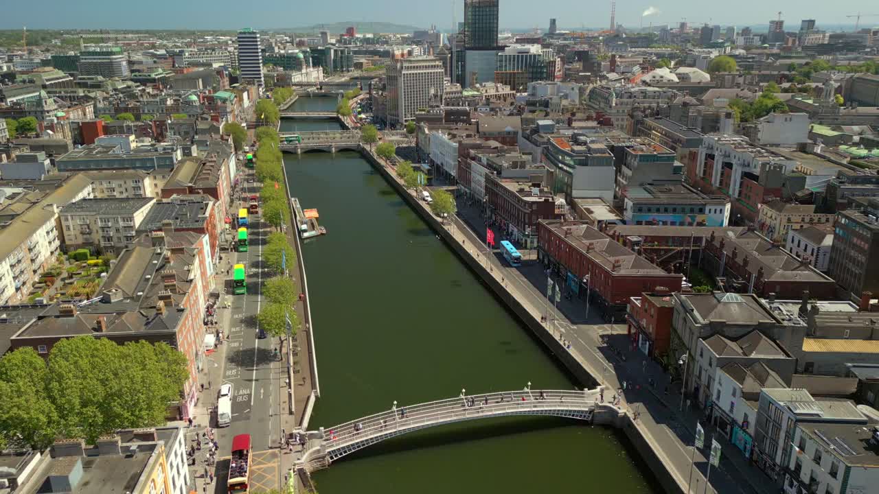 Side-on, forward travelling aerial video of the River Liffey, various bridges and Dublin City Centre in Dublin, Ireland on a bright and sunny day. Filmed in 4K, 60FPS and with Rec709 color.
