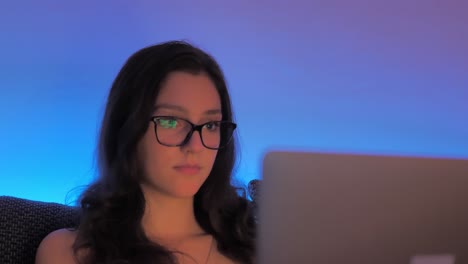 joven bloguera con anteojos trabajando tarde en la noche en una computadora portátil, cierra la cámara lenta