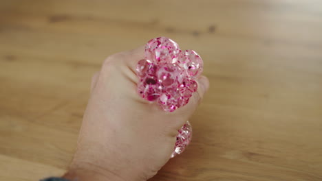 person holding a pink pop it fidget toy on a wooden table