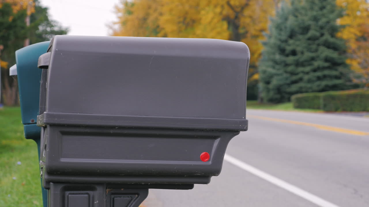 남자가 우체통에 우편물을 넣는다