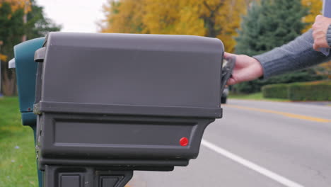 a man puts post in a mailbox