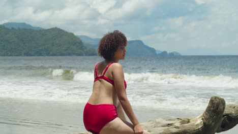 on a sunny day, a young girl with curly hair relaxes in a red bikini on a tropical island