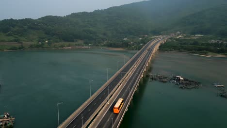 long bridge over waterway with fishing nets and mountains