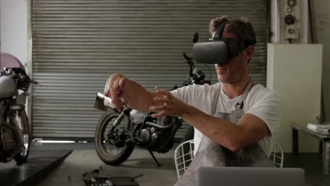 vista frontal de un mecánico caucásico usando auriculares de realidad virtual en un garaje de reparación de motocicletas 4k