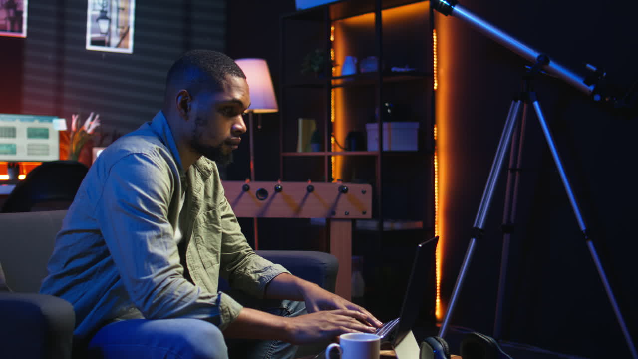 Vertical Video African American young adult working remotely on laptop under loft neon lights