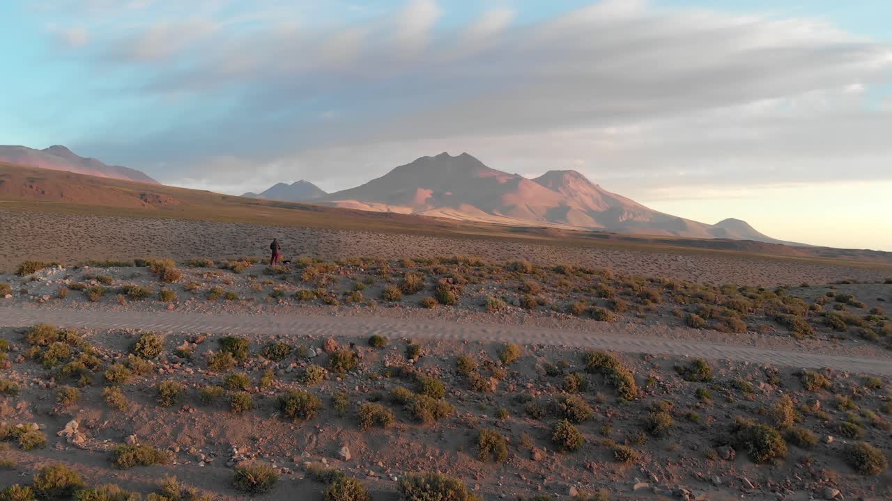 toma cinematográfica aérea de un camino de tierra con un viajero solitario cerca de un acantilado en el desierto de atacama, chile, sudamérica