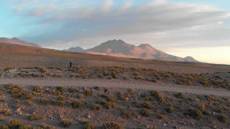 aerial cinematic shot of a dirt road with a lonely traveler near a cliff in the atacama desert, chile, south america