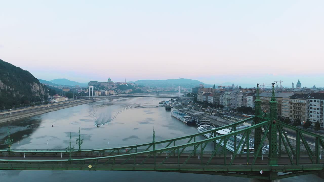 일출, 아침, 전경에 있는 자유의 다리와 함께 부다페스트의 다뉴브 강에서 보트의 공중 드론 샷
