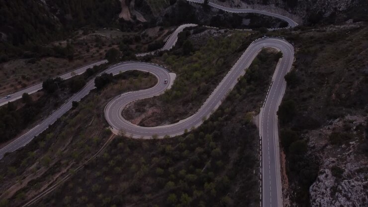 Ripresa aerea di una strada tortuosa ad Alicante, Spagna, con una sola auto che guida lentamente in curva.