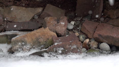 la nieve esponjosa cae suavemente sobre las rocas del lado del arroyo en cámara lenta