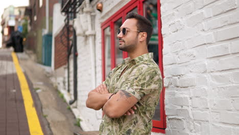 Bearded-Man-Wearing-Sunglasses-Stands-On-Sidewalk-In-Itaewon-District-With-Hands-Crossed-On-Chest