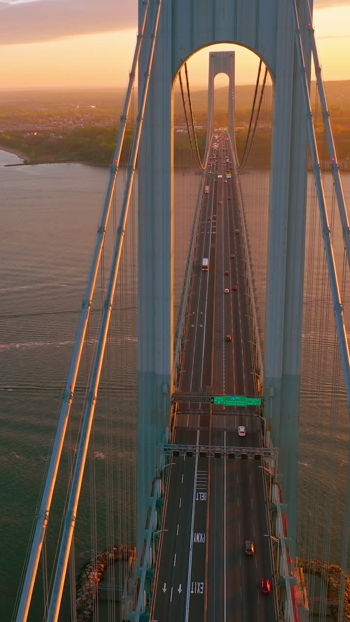Beautiful bridge with motorways for transport. Top view. Huge structure over the river in the rays of setting sun. Vertical video