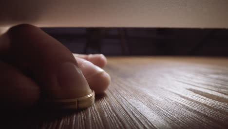 Guy-reaches-to-take-lost-gold-ring-from-under-couch-on-floor