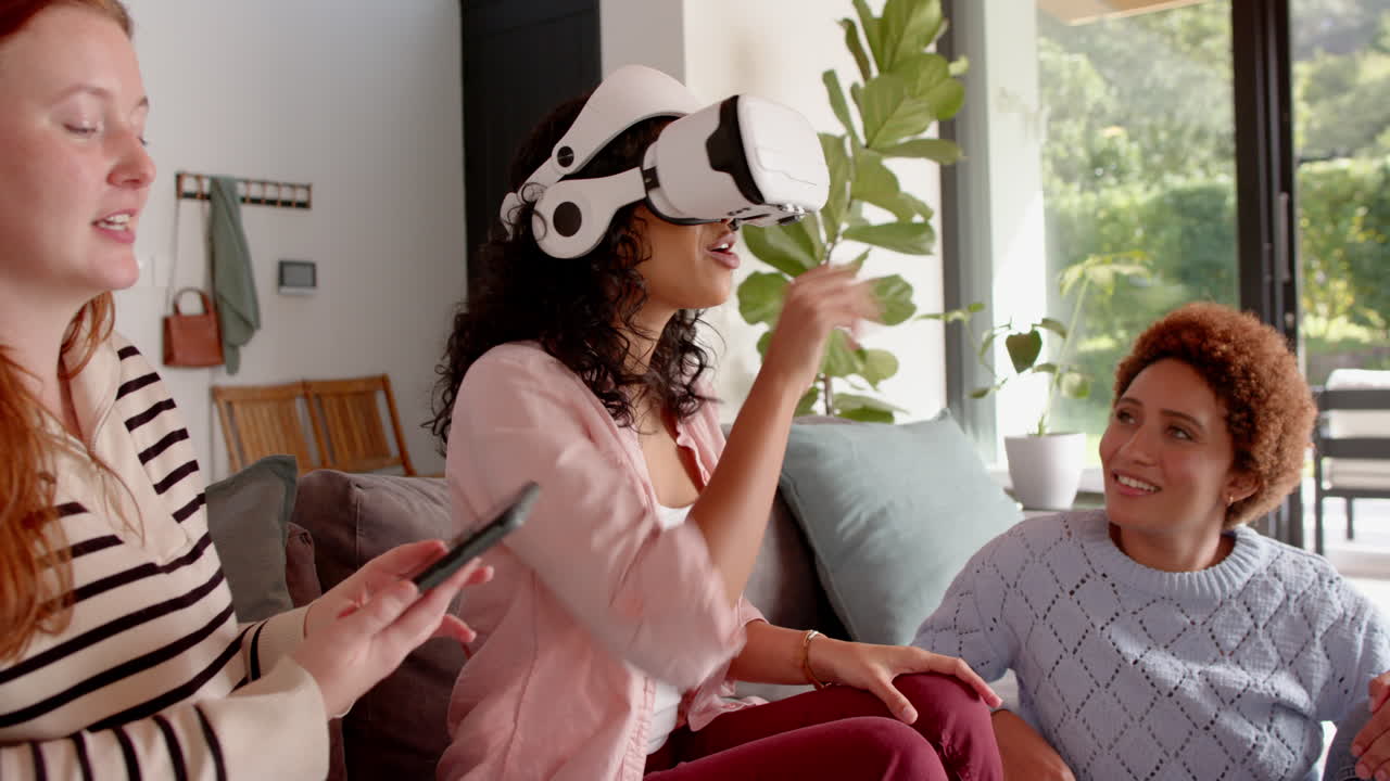Using VR headset, woman interacting with virtual environment while female friends watch
