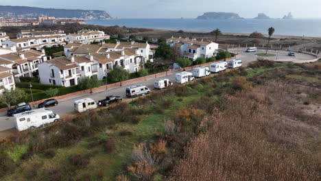 orbiting aerial view row of parked campervans on estartit waterfront overlooking medes islands seascape