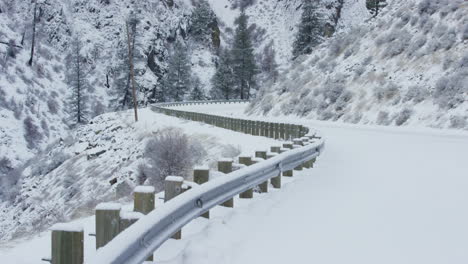 tilting up to reveal massive cliffs towering over snowy rural mountain road