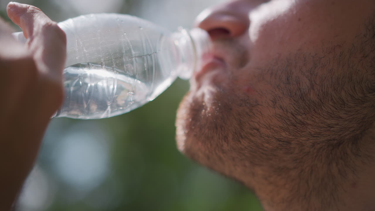 Man Drinks Outdoors, Close View Of Person Rehydrating Outside, Close Up Of Individual Drinking Water In Sunny Outdoor Setting, Detailed Image Of Man Rehydrating In Luminous Park Environment