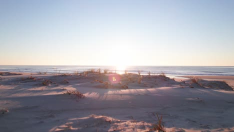 rising reveal of a warming golden sunset across a beautiful beach scene