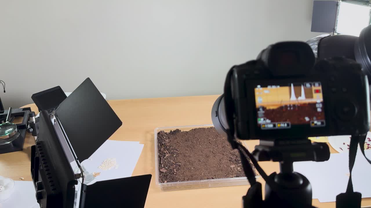 Camera and lighting equipment focus on soil samples in a studio setting, capturing detailed scientific imagery