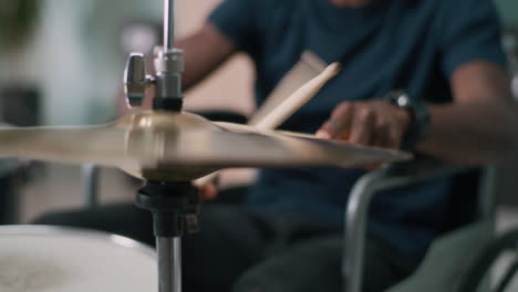 black male with disability enjoying music and playing drums rack focus of young african american female with disability listening to good music in wireless headphones and playing drums during rehearsal in home studio