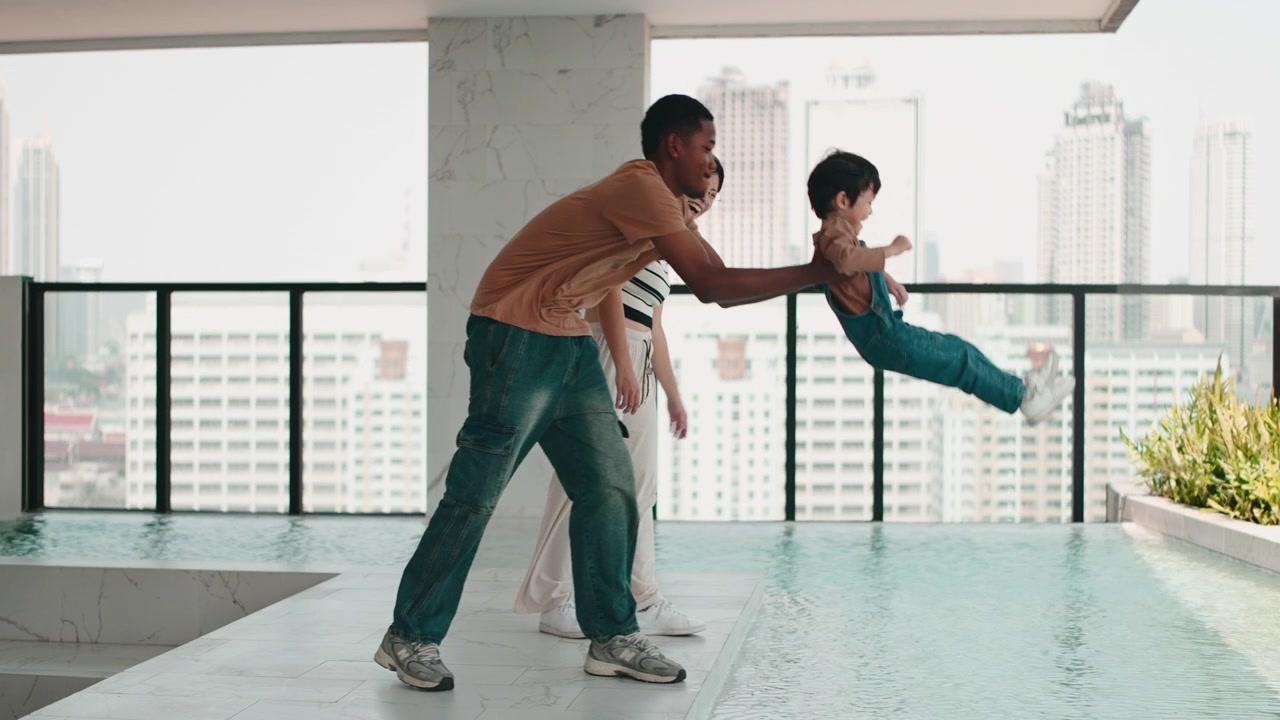 Young Parents Playing with Toddler Son by Rooftop Swimming Pool