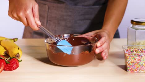 mixing chocolate with spatula, fruits, and sprinkles