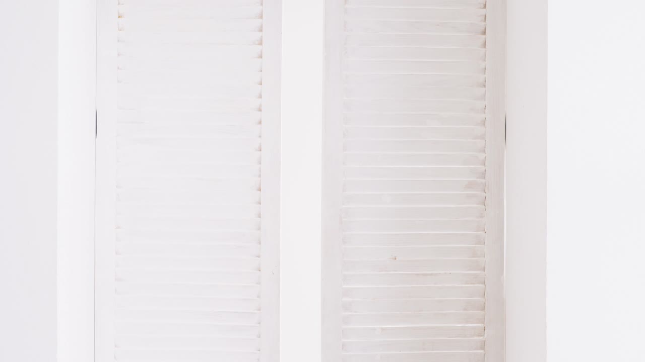 Man standing in a white room with shutters