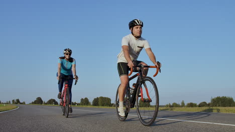 hard training.triathlete two cyclist training on road bicycle. two cyclist riding on road bike in city park and getting ready for triathlon.fit athlete intensive training two man and woman cycling before triathlon competition.