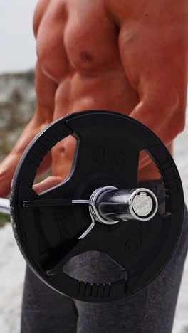 man exercising on nature. athletic fitness man pumping up muscles with barbell outdoor vertical video