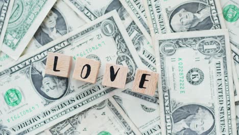 rotating word love from wooden letters, on dollars, concept