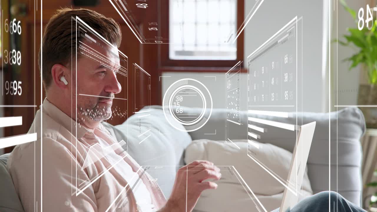 Mature man sitting on sofa, HUD appearing on laptop, gesturing, typing and analyzing tech metrics