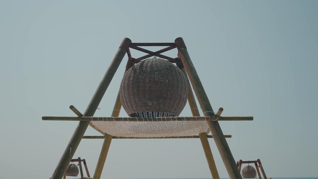 rustic wicker lantern hanging on wooden frame with netting structure under clear sky