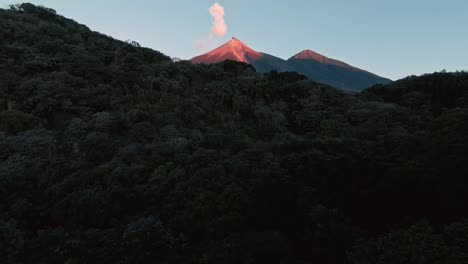 fpv fly through dense tropical jungle revealing lit volcano peak, aerial fpv view