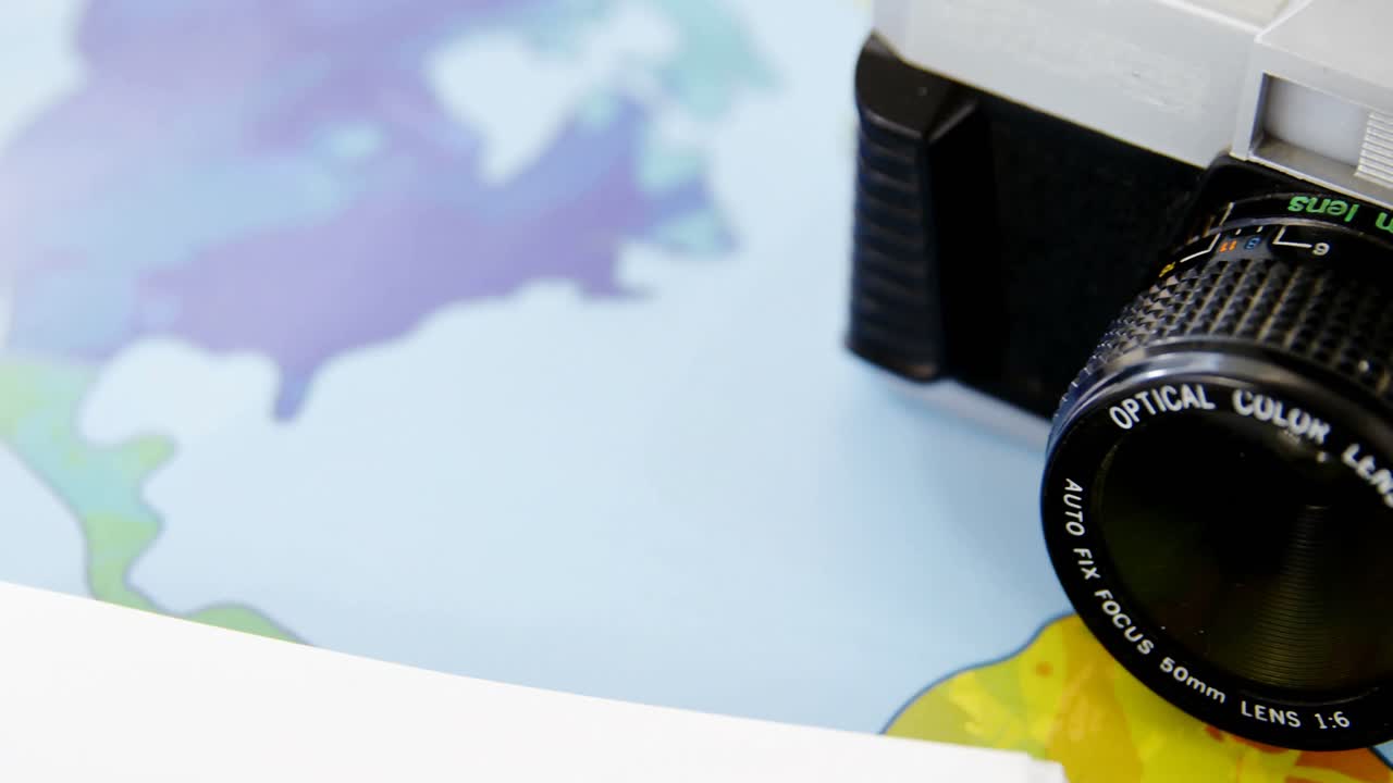 brújula, cámara digital, lechería y modelo de avión en la mesa