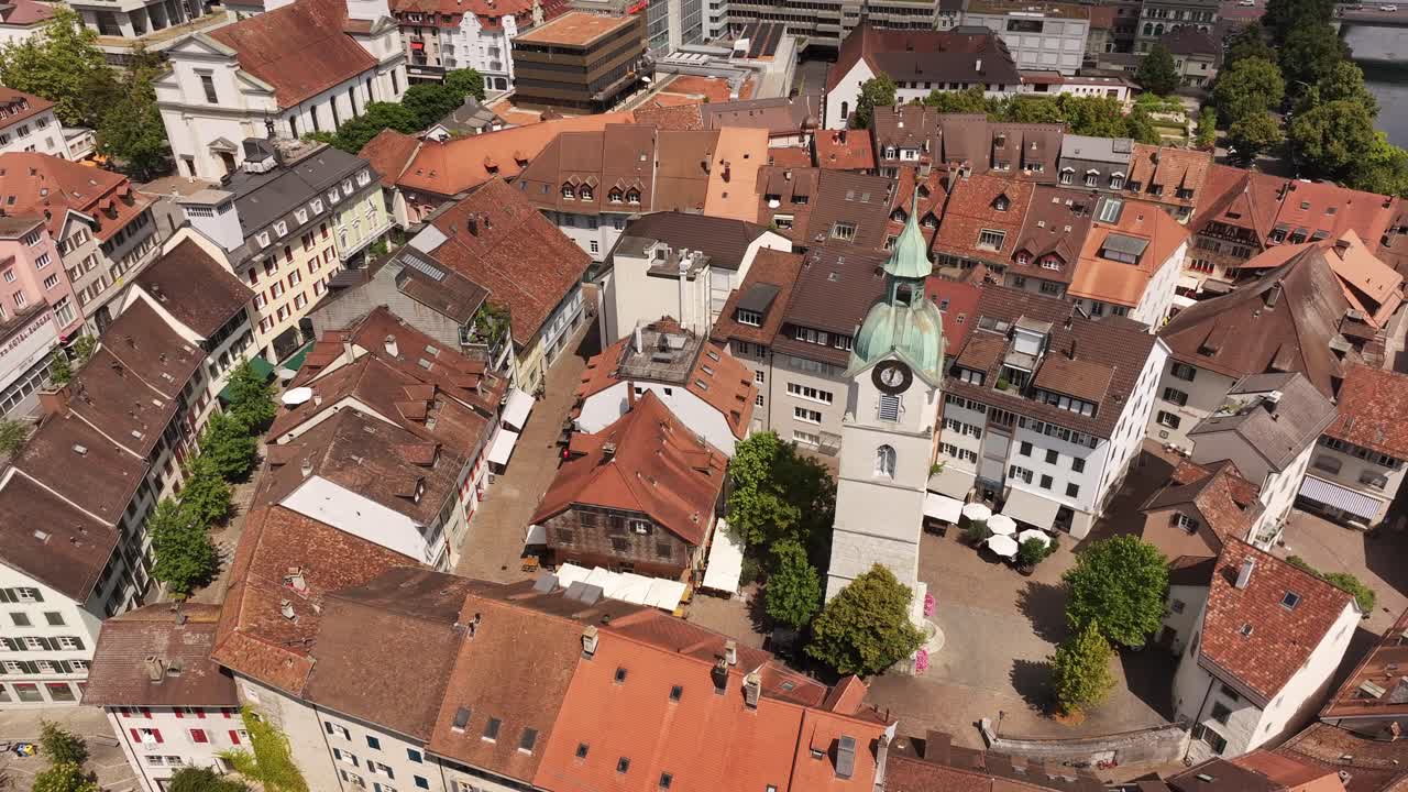 Olten’s red‑roofed old town drone orbits, and covered wooden bridge over the Aare river in Canton Solothurn, Switzerland, historic city center, green hills, serene aerial