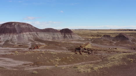 drone flying backward over a dusty badland on a sunny day