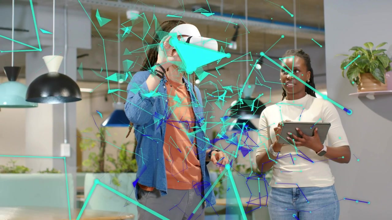 Utente VR che indossa il visore, utente di tablet che monitora frammenti color verde acqua che si muovono durante una demo tecnologica in una lounge d'ufficio