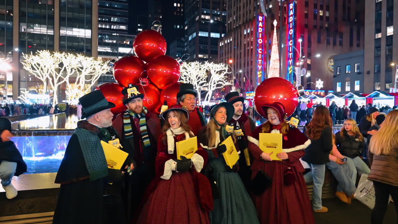 New York, USA, 5. desember 2025: Viktorianske julesangere opptrer i nærheten av Rockefeller Center. En gruppe julesangere i historiske kostymer synger ved siden av opplyste trær og gigantiske ornamenter på et travelt offentlig område