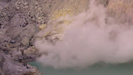 the smoke of sulfur mining mountain volcano crater with acidic of kawah ijen lake in east java indonesia.