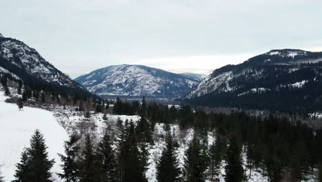 Montañas-Cubiertas-De-Nieve-Y-Un-Hermoso-Bosque-En-Un-Pequeño-Fuerte,-Bc:-Vista-Aérea-De-Vuelo-Inverso