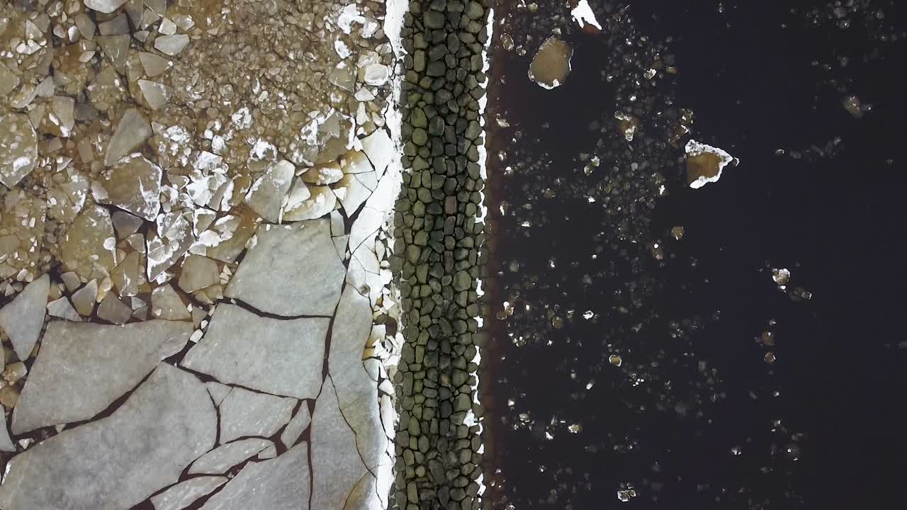 A top-down aerial drone view of a mole breaking down the ice during winter