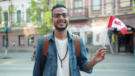 smiling man holding canadian flag in city