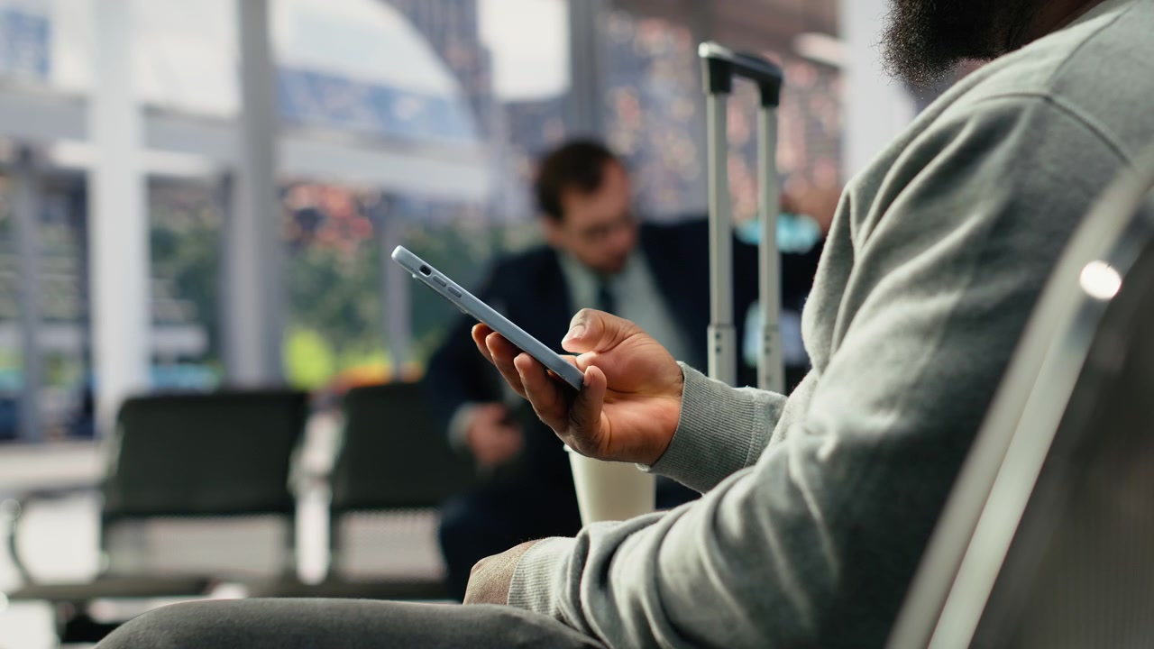 Close up of passenger texting friends on phone in bus station