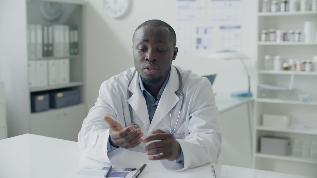 Médecin noir parlant à la caméra lors d'une consultation virtuelle avec un patient